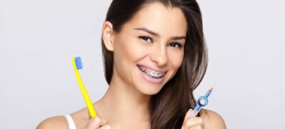 Young woman with braces and toothbrush and braces brush cleaner