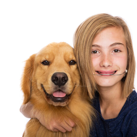 image of a child hugging a dog wearing orthodontic headgear and smiling at the camera